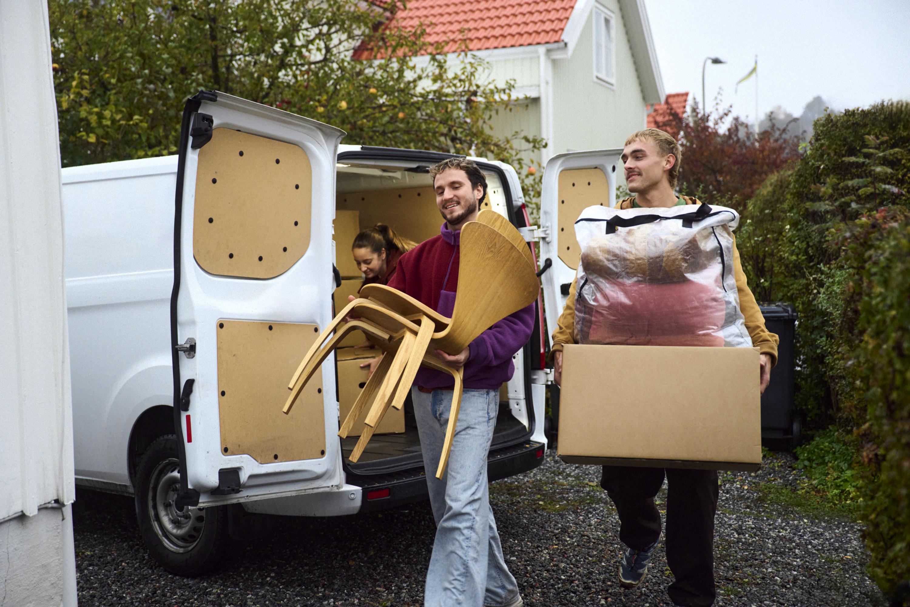 Personer bär flyttlådor och möbler vid en flytt.