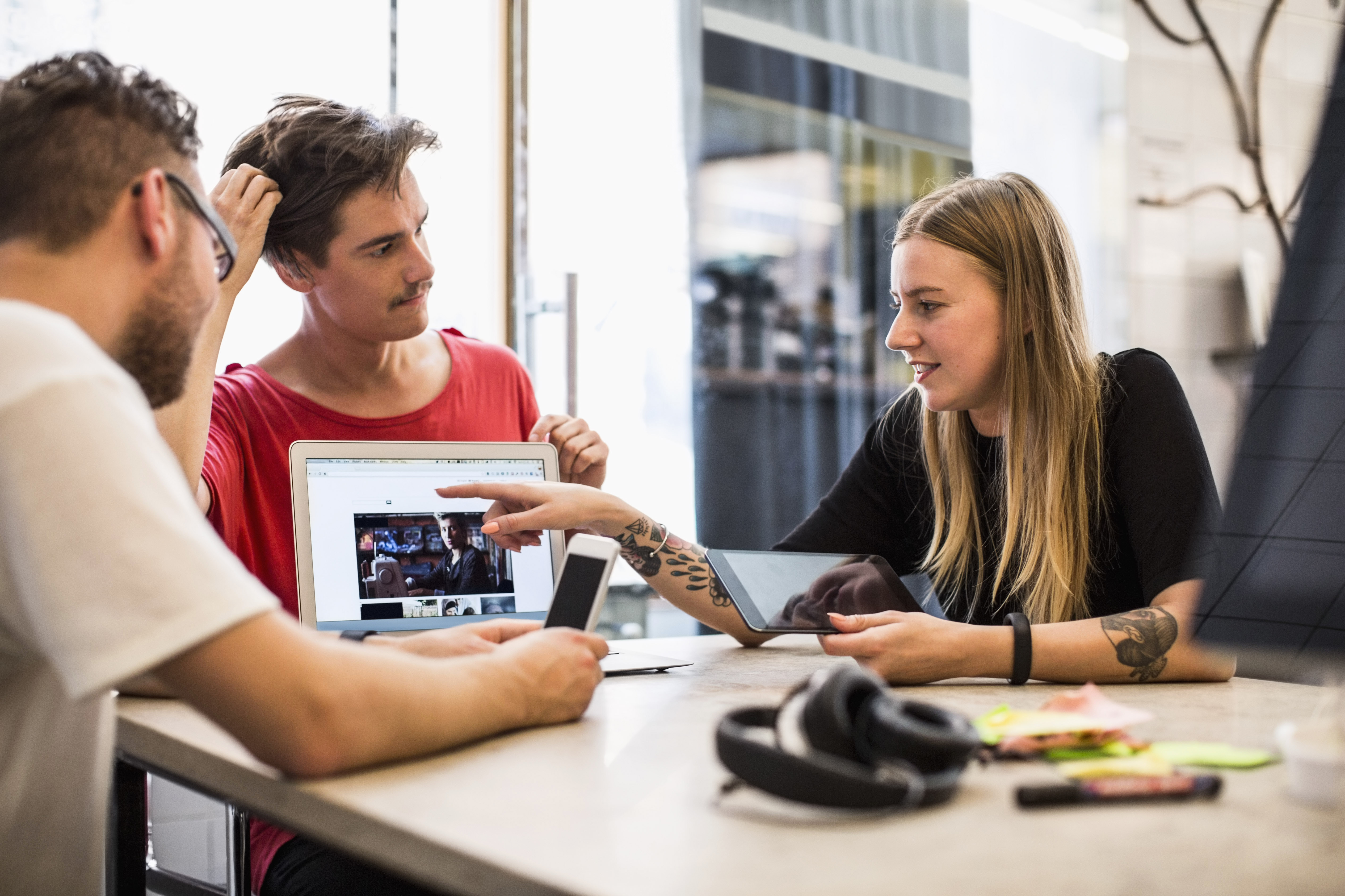 Tre personer sitter vid ett bord och tittar tillsammans på en skärm