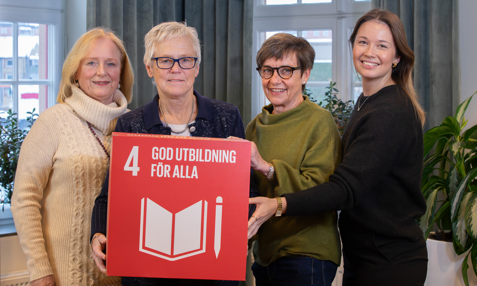fyra personer håller i en kub FN:s globala mål 4